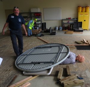 Jim Reagan, one of the CERT instructors, begins covering "Rescue Randy" with assorted debris to simulate the aftereffects of a building collapse. 
