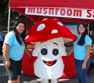 Two volunteers share a moment with Fun Gus, the official mascot of The Mushroom festival, during the 2012 event.