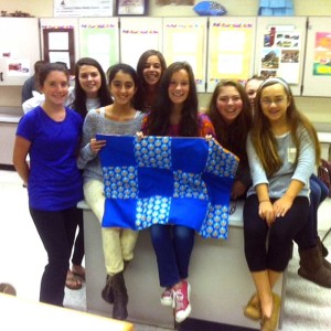 It's finished! Patton students (left to right) Rebecca Peakes, Taryn Thompson, Leah Narun, Sophia Kolliopoulos, Helen Nichols, Lara Jensen, Ariana Birney, and Natalie Pechin proudly show off their completed quilt as part of the Patton Project. The quilt will be given to a child at A.I. duPont Hospital for Children.