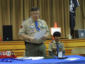 Scoutmaster, Ray Coe, awards Eagle recipient, Walip Yenbutr, with the highest rank in Boy Scouts, Eagle Scout 
