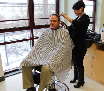 Jessica Hernandez gives barbering instructor Drew Givler a haircut in the barbershop at TCHS Brandywine.