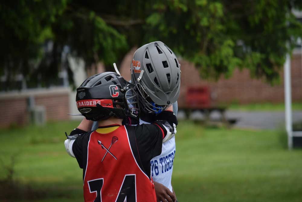 The first-ever Red Raider Rumble brought lacrosse teams from around the region and as far away as New York City to partipate in a day competition, fun and sportsmanship. After a very close and exciting game, these players from Coatesville and Harlem came together for a hug — a true sign of sportsmanship. Credit: Stacy Geyer